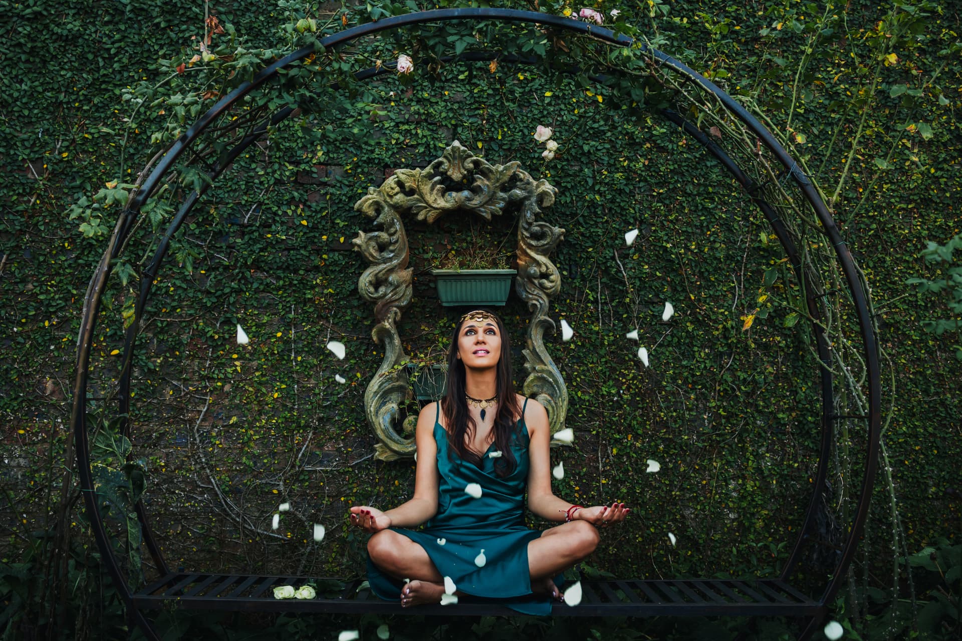 Noa seated in meditation beneath a circular garden arch