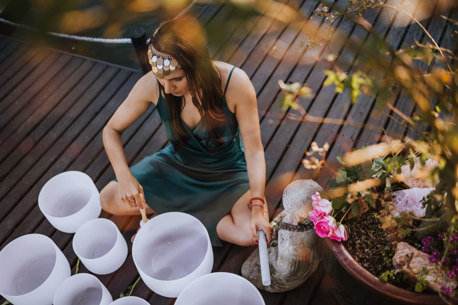 Noa playing crystal singing bowls on a sunlit wooden deck